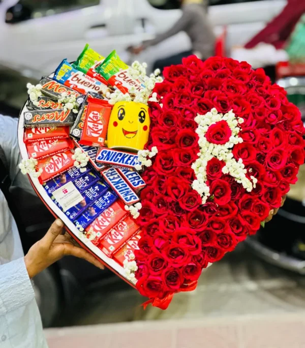 Heart-shaped arrangement of flowers and chocolates