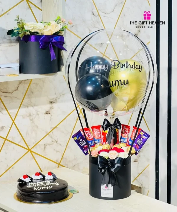 Luxury birthday hot air balloon chocolate gift box with premium balloons, KitKat, Cadbury Dairy Milk, Ferrero Rocher chocolates, elegant floral arrangement, and black luxury gift box by The Gift Heaven Bangladesh.